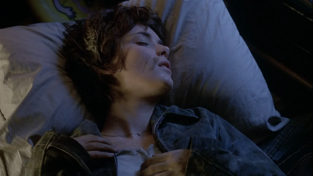 Boys (2021) movie still: closeup — A dark bedroom with a white pillow and a person resting on it. A woman with short dark hair rests her head on the…