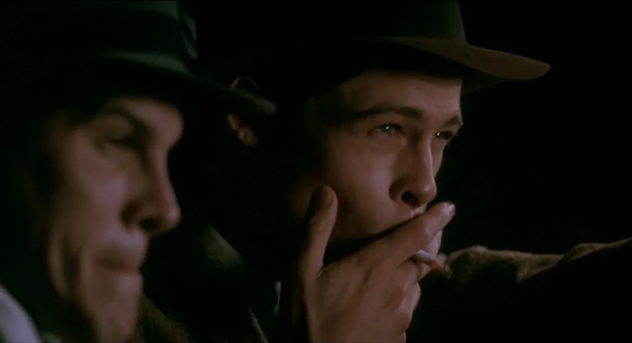 A River Runs Through It (1992) movie still: medium — A dark, dimly lit vehicle interior during the night features two men wearing fedoras. A younger…