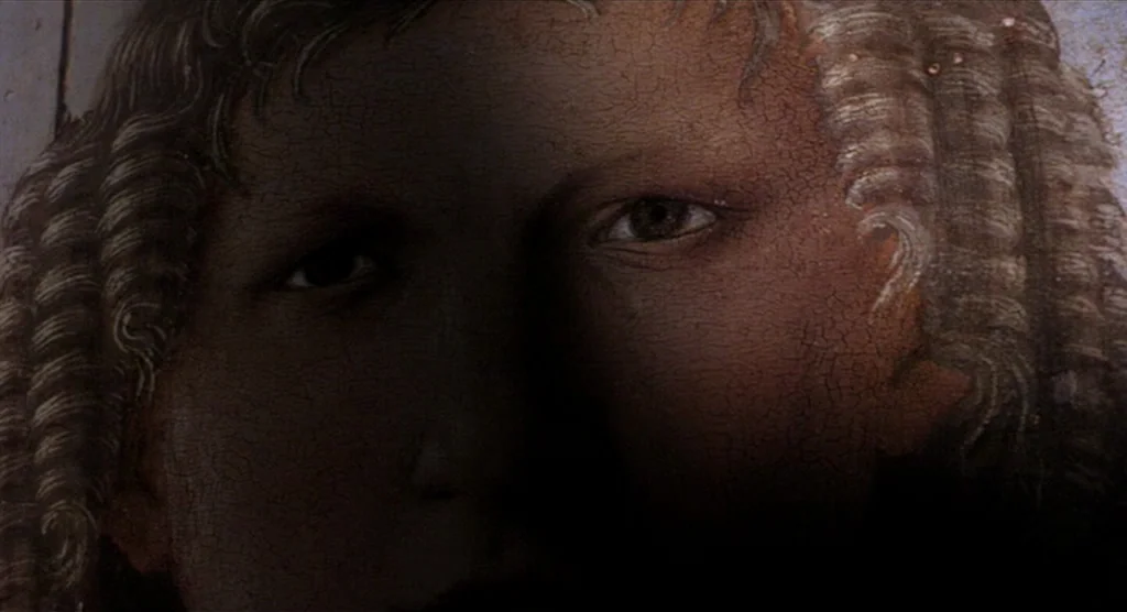 King Lear (1987) movie still: closeup — A close-up view of a cracked, textured painted surface depicting a human face. A sharp vertical shadow…