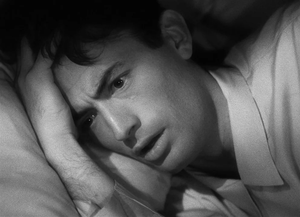 Spellbound (1945) movie still: closeup — A man is lying down in a bed during the nighttime. He rests his head on a pillow while looking toward the…