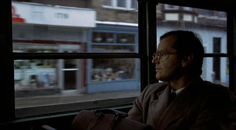 The King Of Marvin Gardens movie still: medium — A man sits on a bus with a blurred city street passing by outside. He gazes through the window…