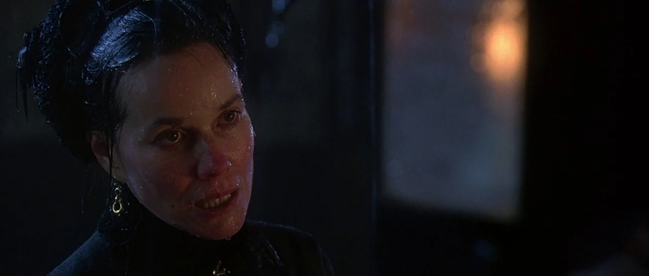 The Portait of a Lady (1996) movie still: closeup — A woman stands in a dimly lit dark space with visible moisture on her skin. She gazes slightly…