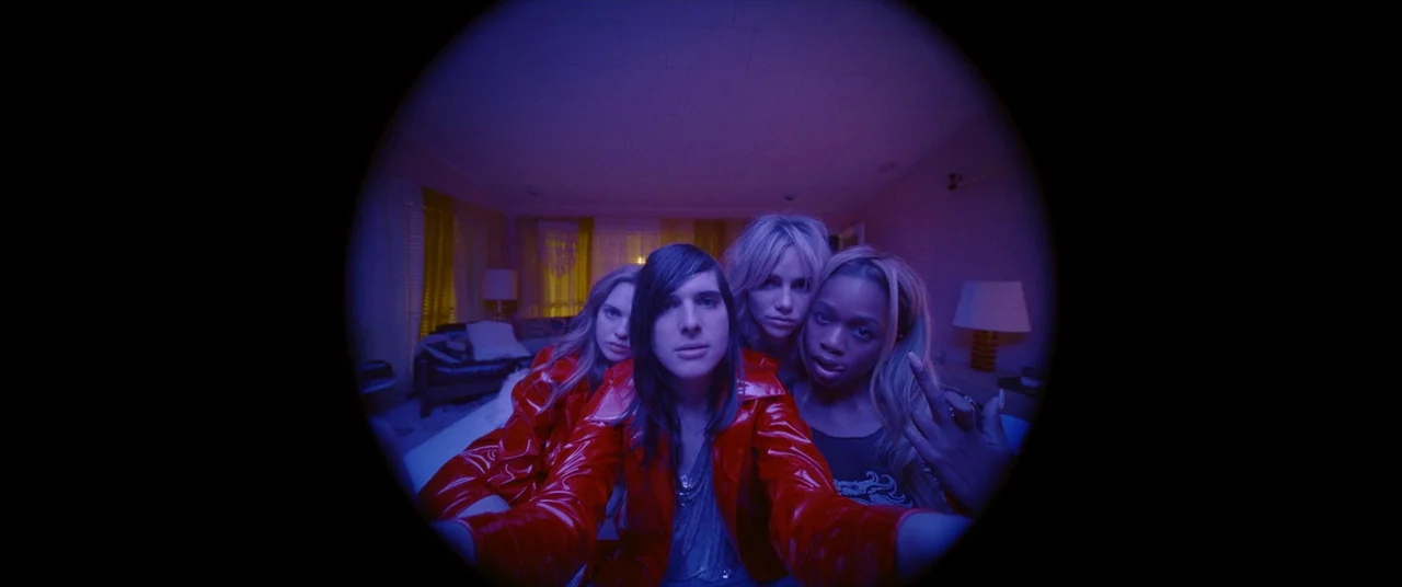 Assassination Nation (2018) movie still: medium — A group of four young adults poses for a camera in a blue-lit interior space. The subjects are…