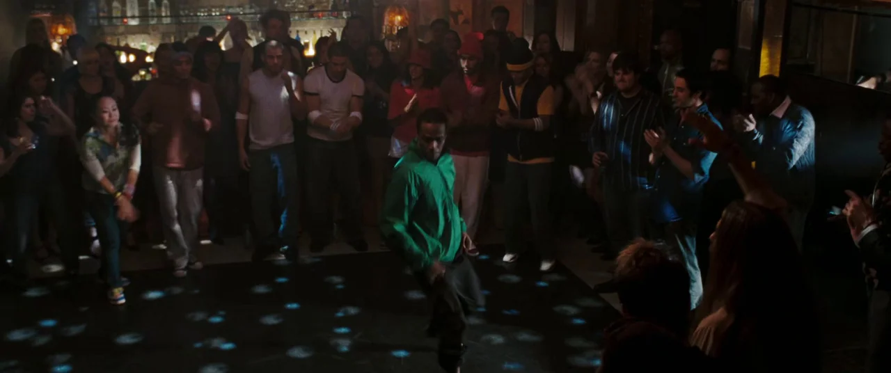 Two Lovers (2008) movie still: fullbody — A crowded dance floor in a dark bar with people watching a dancer. A man in a bright green jacket performs…