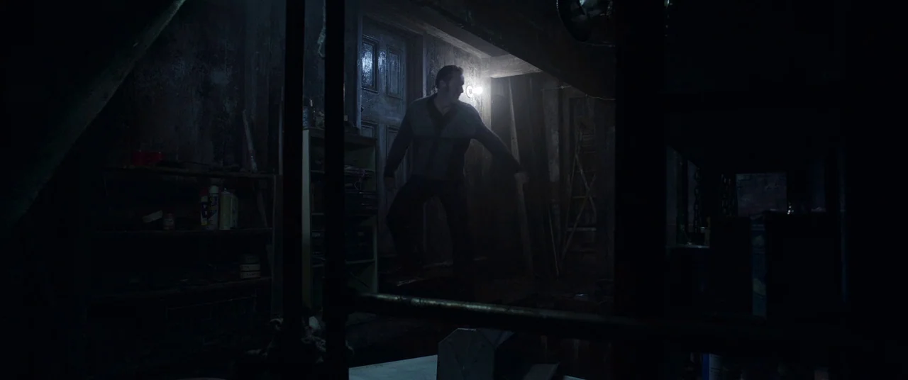 The Conjuring 2 (2016) movie still: medium — A dark, cluttered basement contains wooden shelving units and miscellaneous household items. A man…