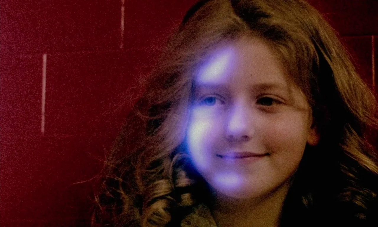 Paganini Horror (1989) movie still: closeup — A person stands before a dark red wall with horizontal indentations. Blue light highlights the…