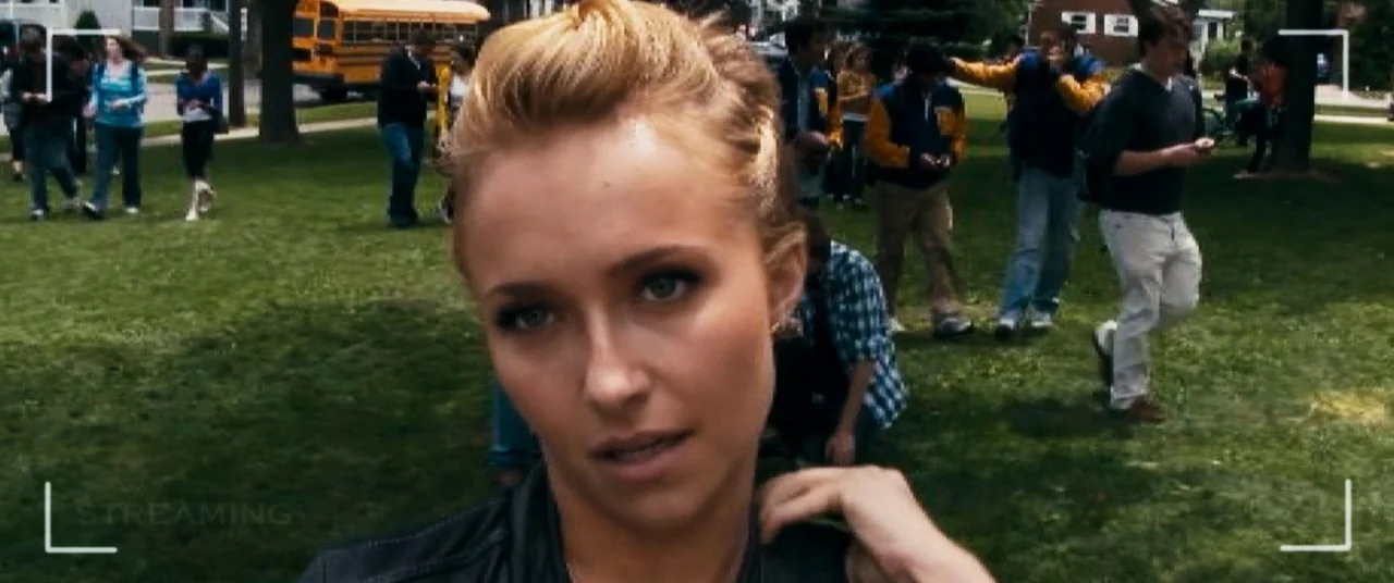 Scream 4 (2011) movie still: closeup — A group of high school students walk on a green campus lawn during the day. A young woman in the foreground…