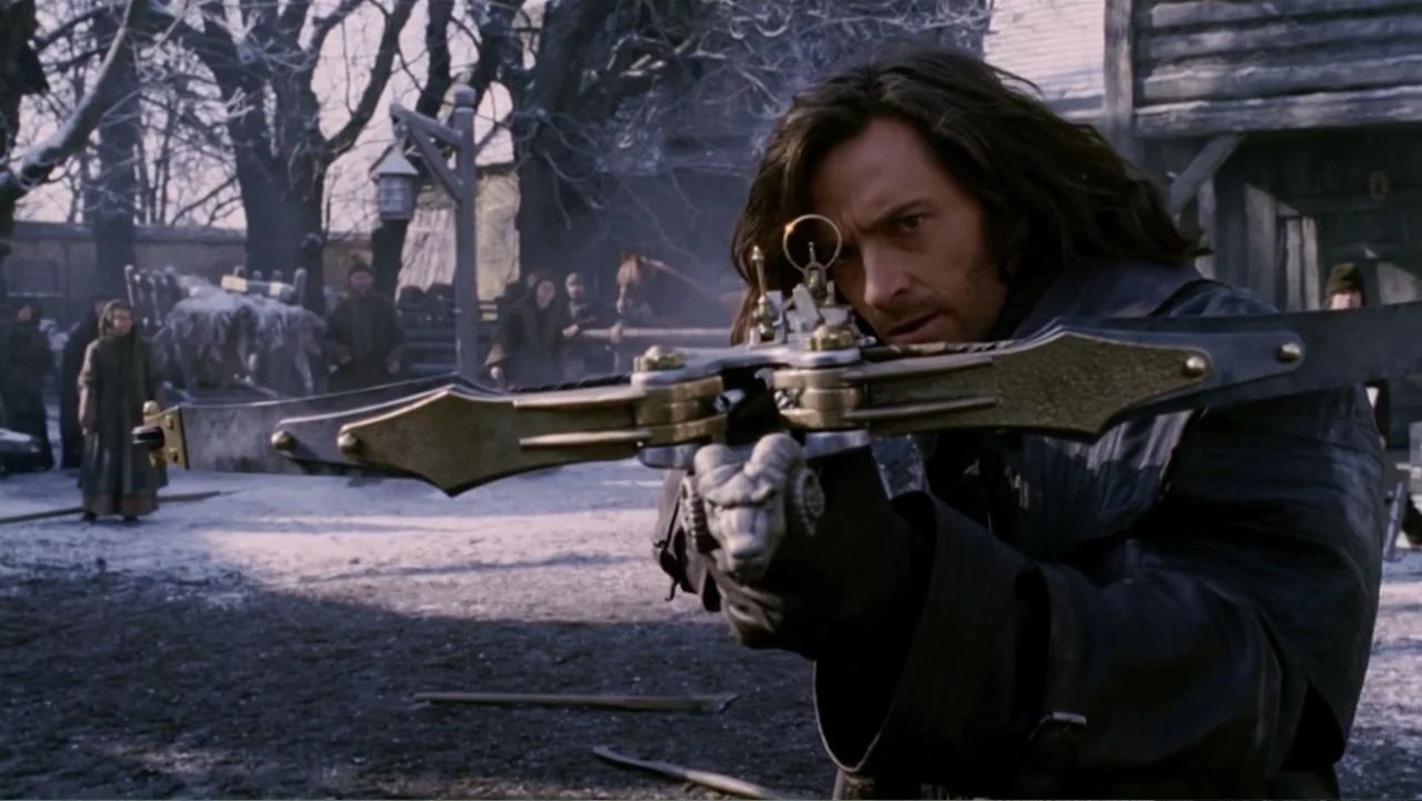 Van Helsing (2004) movie still: medium — A snowy, rustic village square contains wooden buildings and bare trees in the background. A man holds a…