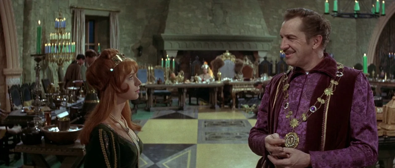 The Masque of the Red Death (1964) movie still: medium — A stone-walled great hall is furnished with wooden tables and large chandeliers. A…