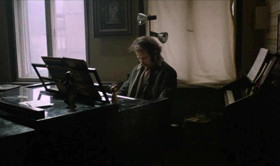Stroszek (1977) movie still: medium — A dark, cluttered interior space with a window draped in white cloth. A man in a dark coat sits at an upright…