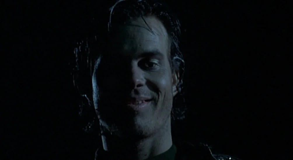 Near Dark (1987) movie still: closeup — A dark, undefined space serves as the backdrop for a close portrait. A man looks directly into the camera…
