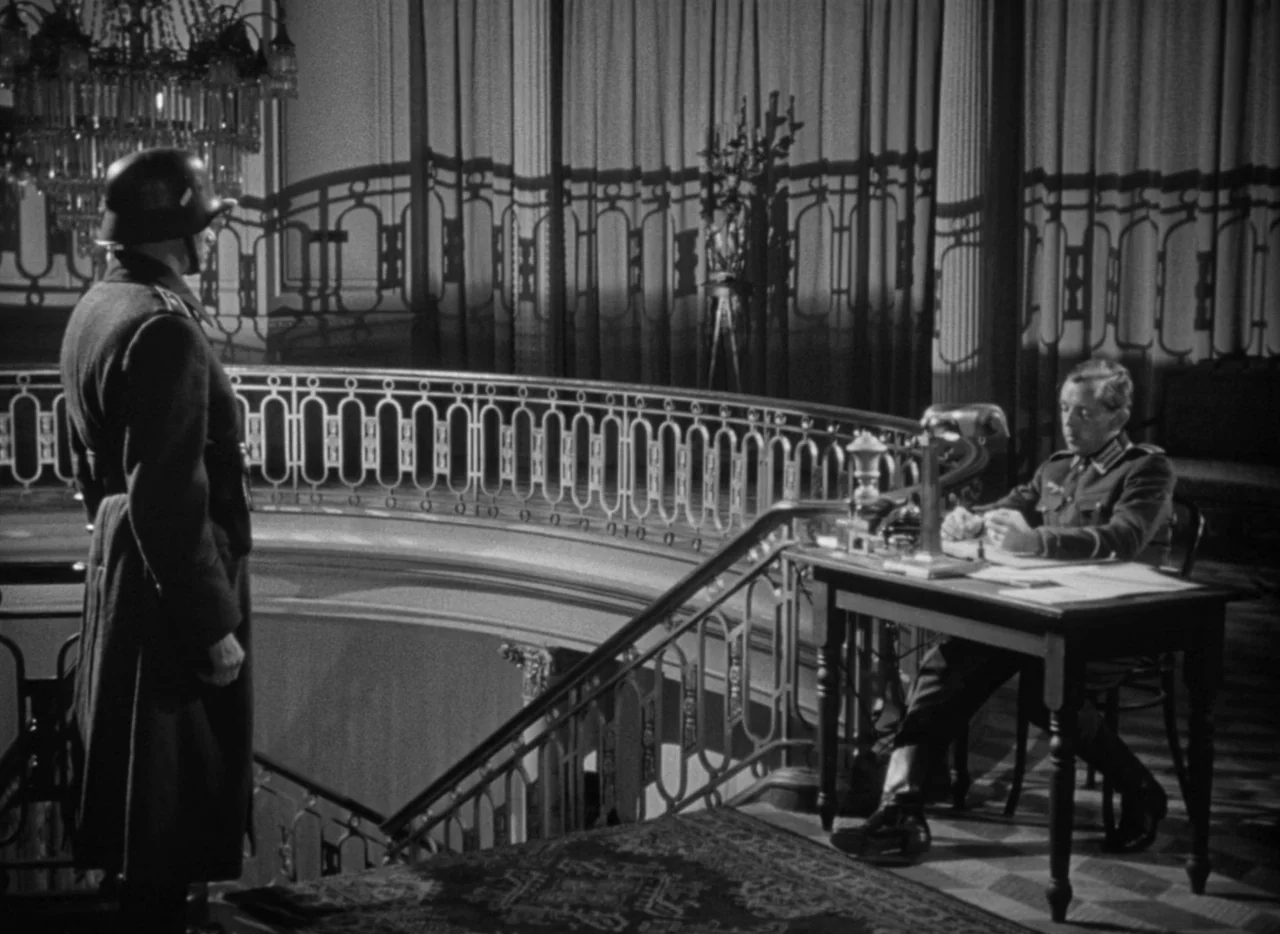 To Be or Not To Be (1942) movie still: wide — An ornate mansion landing features grand floor-to-ceiling curtains and a large glass chandelier. One…