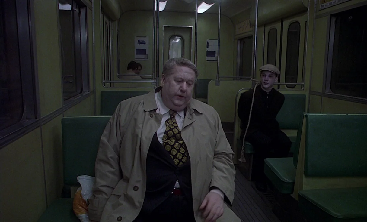 Songs from the Second Floor (2000) movie still: medium — An aging subway car features green vinyl seating and metal handrail poles. An older man in…