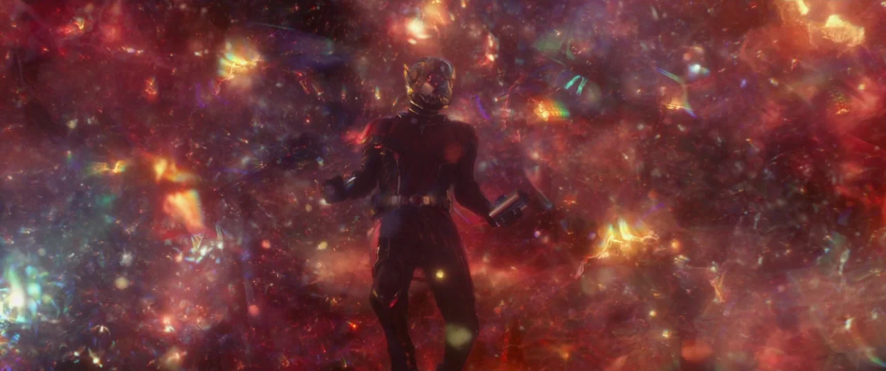 Ant-Man and the Wasp (2018) movie still: fullbody — A figure in a technological suit drifts through a vibrant, dense cloud of light. Swirling…