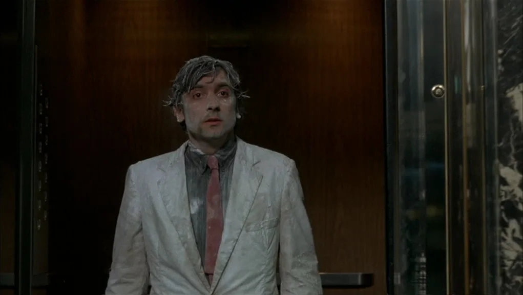 After Hours (1985) movie still: medium — A cramped wood-paneled elevator interior with stainless steel buttons visible on the left. A man wearing a…
