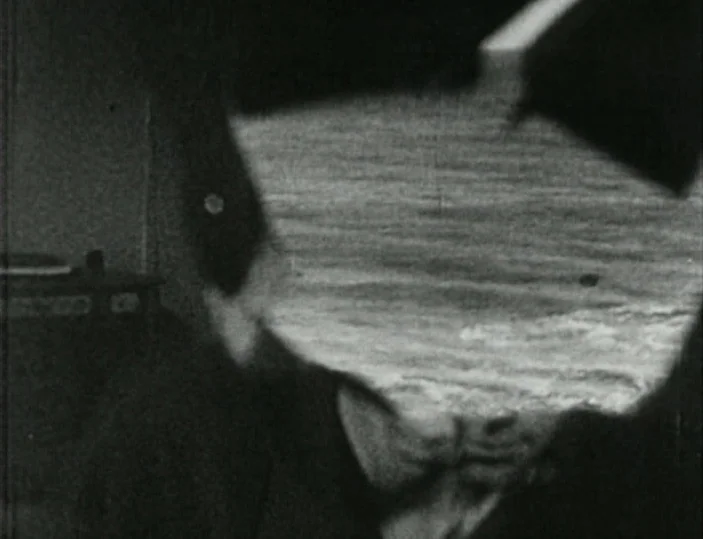 Meshes of the Afternoon (1943) movie still: closeup — A dimly lit interior space is visible in the background behind the subject. A double-exposed…