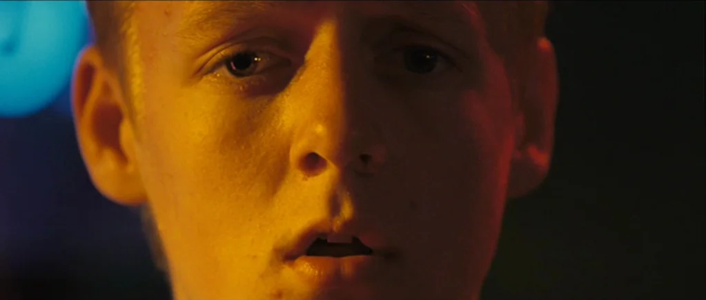 The Scouting Book for Boys (2009) movie still: closeup — A dimly lit space features a man captured in a tight closeup frame. The subject faces the…