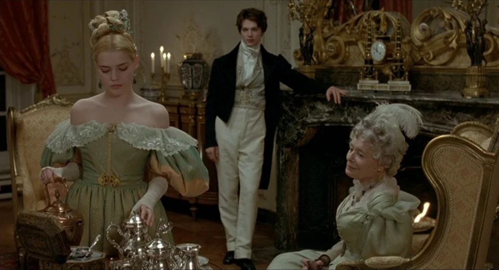 The Last Mistress (2007) movie still: fullbody — An opulent 19th-century drawing room with ornate gold trim and an active fireplace. A young woman…