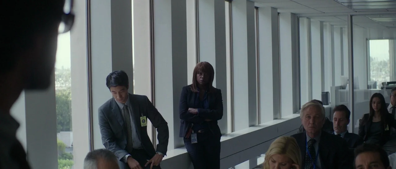 Blackhat (2015) movie still: wide — A modern, sterile room with tall windows and vertical mullions lining the far wall. Multiple people sit and…