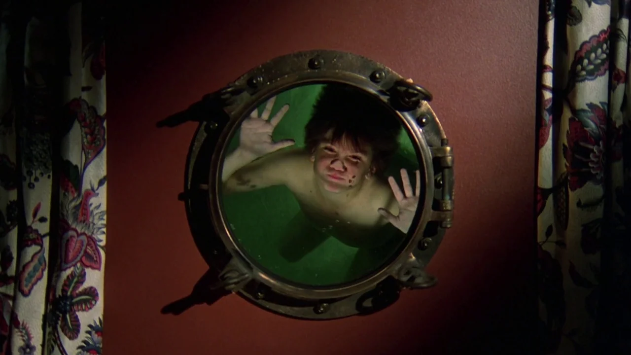 Friday the 13th Part VIII: Jason Takes Manhattan (1989) movie still: closeup — A brass-rimmed circular porthole is embedded into a solid deep-red…