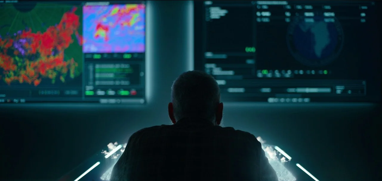 The Midnight Sky (2020) movie still: medium — A dark, modern command center features large wall displays showing complex meteorological data maps. A…