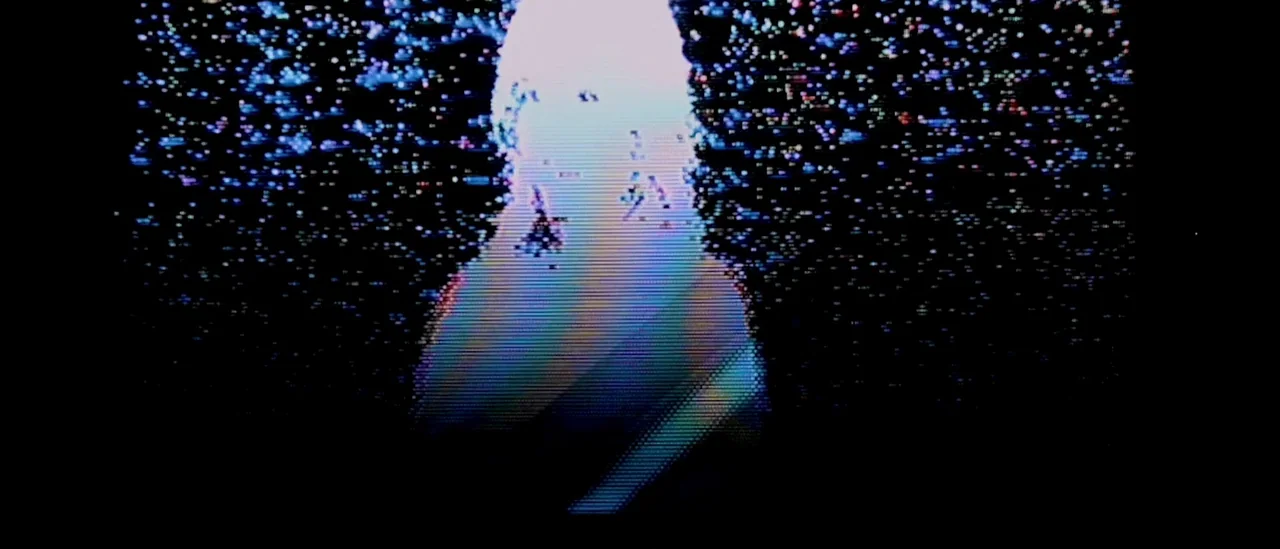 I Trapped The Devil (2019) movie still: medium — A figure stands in a dark space filled with heavy analog video signal distortion. The image is…