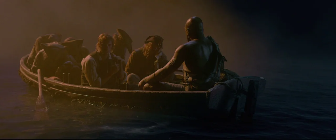 Pirates of the Caribbean: On Stranger Tides movie still: wide — A small wooden rowboat carries a group of men across dark water at night. A large,…