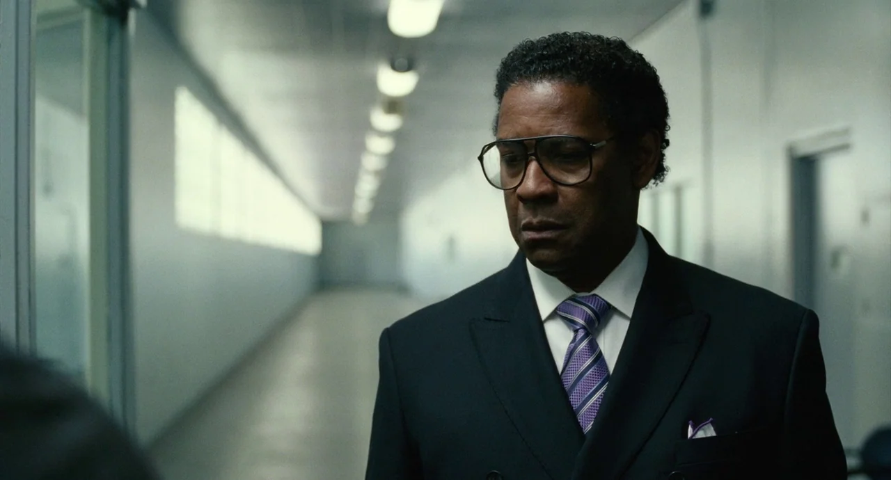 Roman J. Israel, Esq. (2017) movie still: medium — A long, sterile hospital hallway with white walls and a polished floor. A man in a suit looks…
