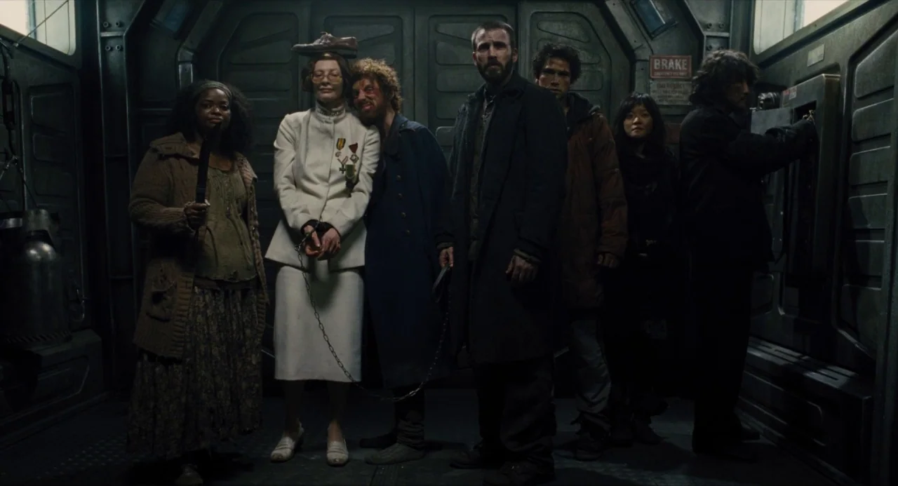 Snowpiercer (2013) movie still: fullbody — A narrow metal-walled train carriage with mechanical wall panels and a brake sign. Six people stand in a…