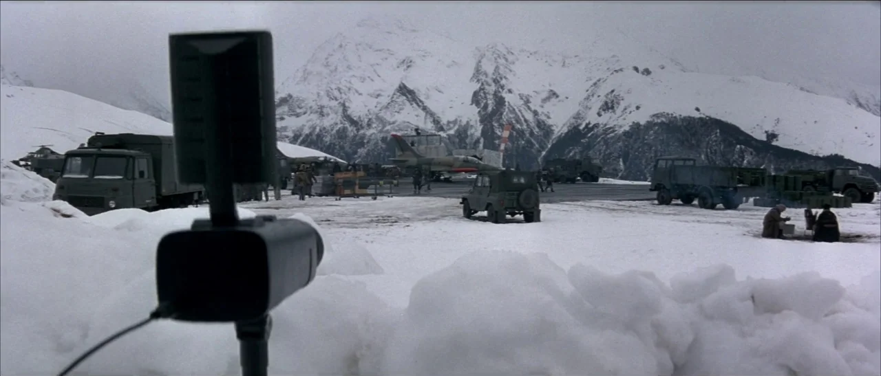 Tomorrow Never Dies (1997) movie still: wide — A snowy, high-altitude military airfield surrounded by massive, jagged, snow-capped mountains.…