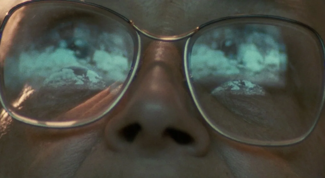 Patagonia (2010) movie still: closeup — An extreme close-up focuses on a pair of glasses reflecting a bright digital screen. The wearer's nose and…