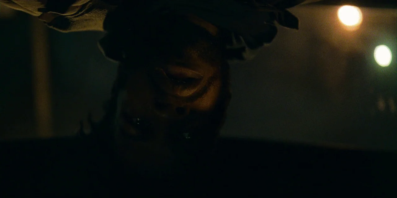 They Cloned Tyrone (2023) movie still: closeup — The interior of a vehicle at night featuring a man positioned upside down. The man looks toward the…