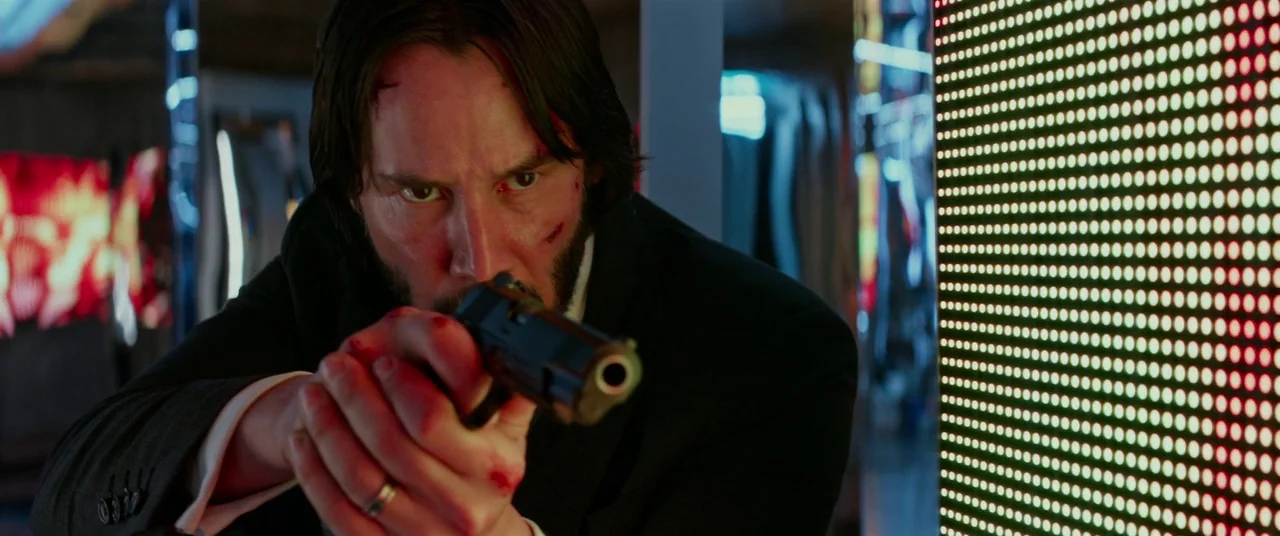 John Wick: Chapter 2 (2017) movie still: closeup — An interior space decorated with large, vertical illuminated LED display panels showing abstract…