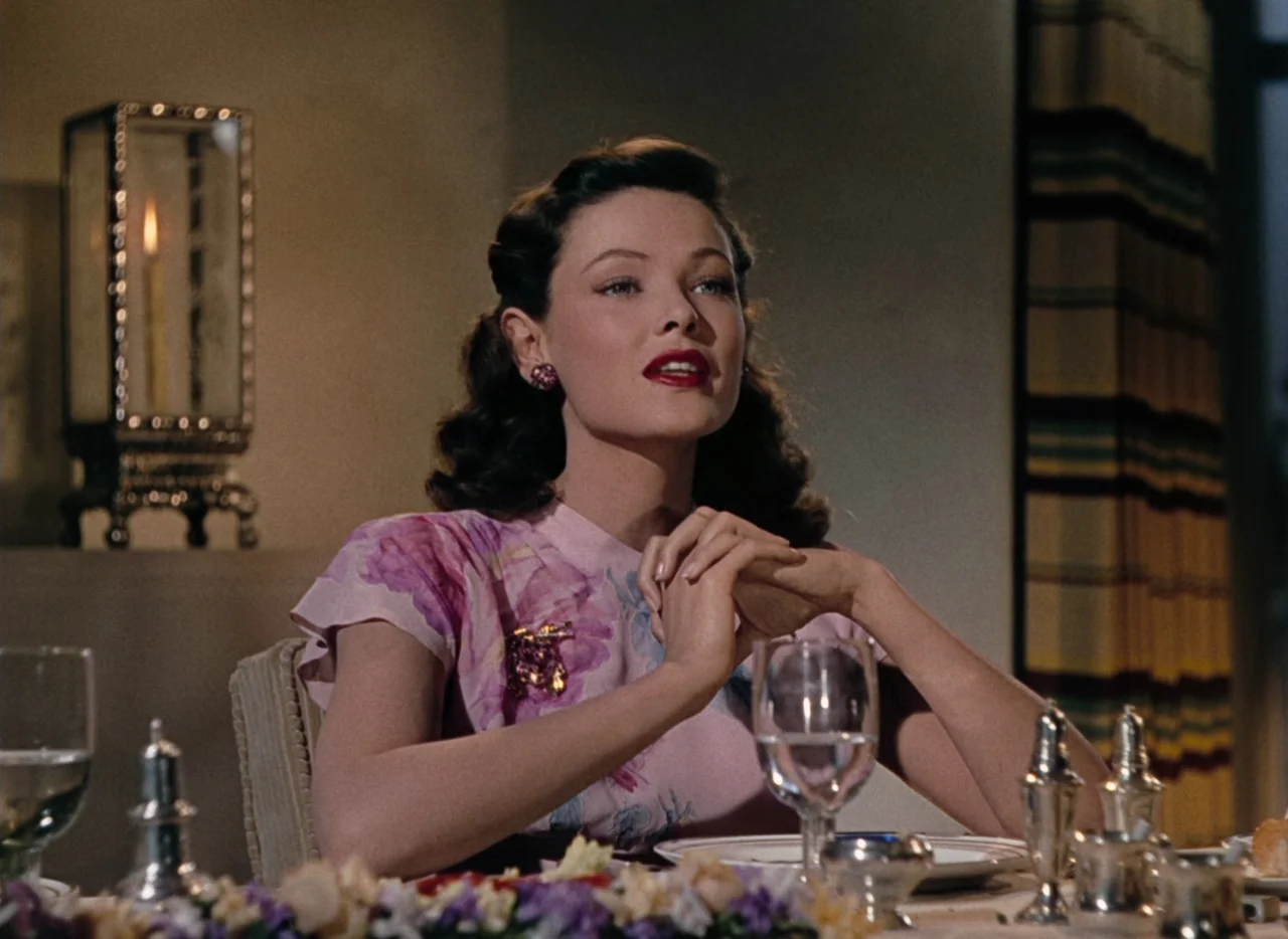 Leave Her To Heaven (1945) movie still: medium — A woman sits at a dinner table in a dimly lit room with vintage decor. She is focused forward with…