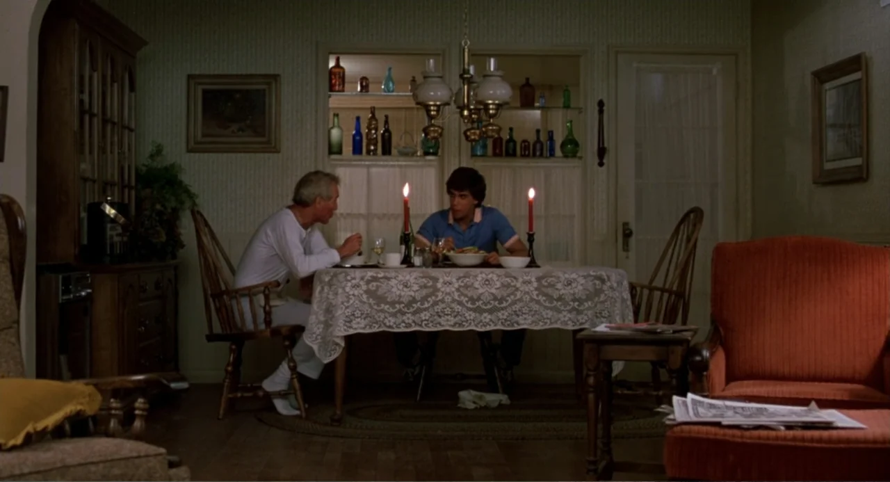 Harry and the Butler (1961) movie still: medium — A residential dining room features floral wallpaper and wooden furniture with a lace tablecloth.…