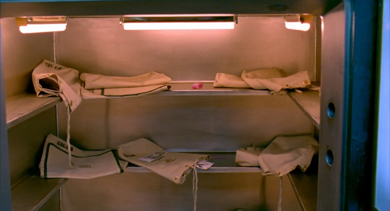 The Good Thief (2002) movie still: medium — A stainless steel bank vault interior contains multiple beige canvas money bags on shelves. The bags are…