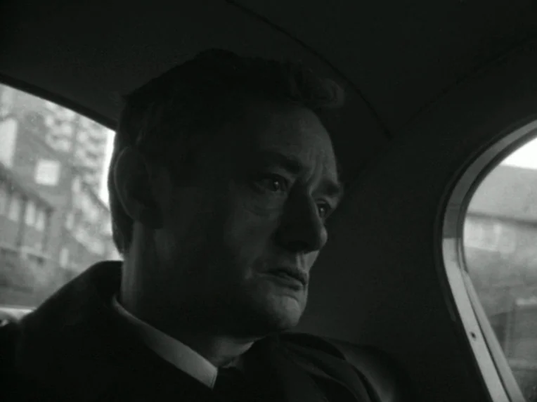 Death and Transfiguration (1983) movie still: closeup — The interior of a moving vehicle is captured in black and white tones. A man sits in the…