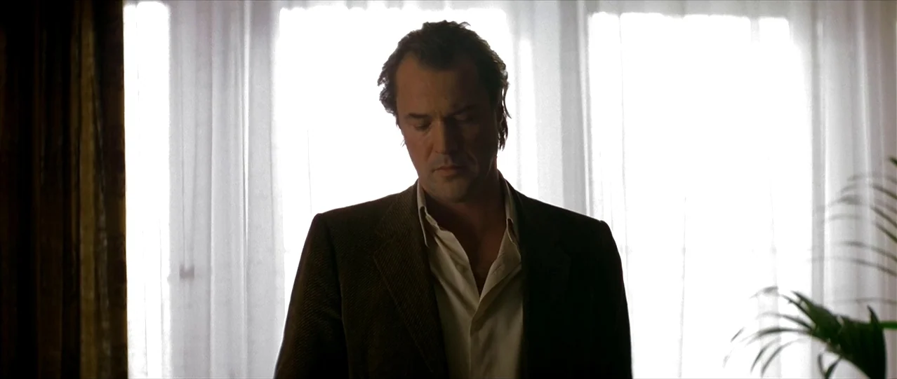 The Lives of Others (2006) movie still: medium — A man stands before a bright, window-lit space with sheer white curtains. He looks downward toward…