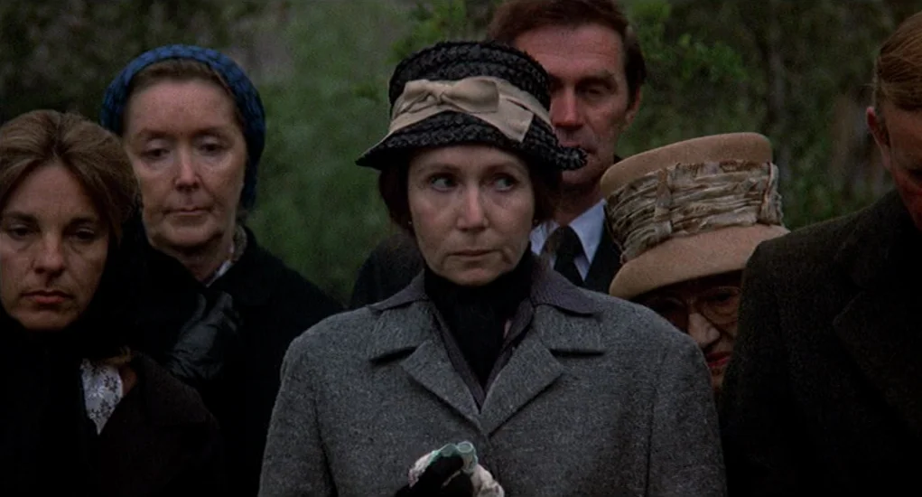 Family Plot (1976) movie still: medium — A group of people wearing formal attire stands close together outdoors. The individuals look forward while…