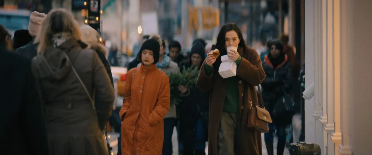 Something from Tiffany's (2022) movie still: medium — A crowded city sidewalk filled with pedestrians on a busy urban day. A woman walks toward the…
