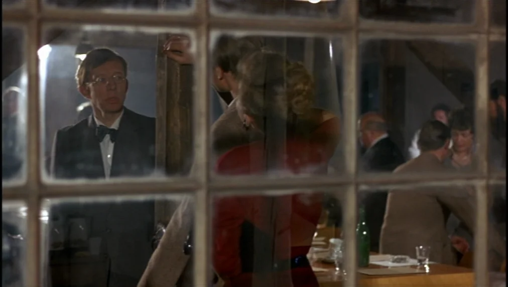 The Marriage of Maria Braun (1979) movie still: medium — An interior space is viewed through a grid-patterned window with several people seated at…