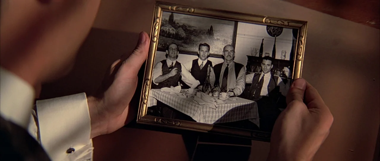 The Untouchables (1987) movie still: closeup — A person holds a black and white photograph depicting four men at a table. The men in the picture…
