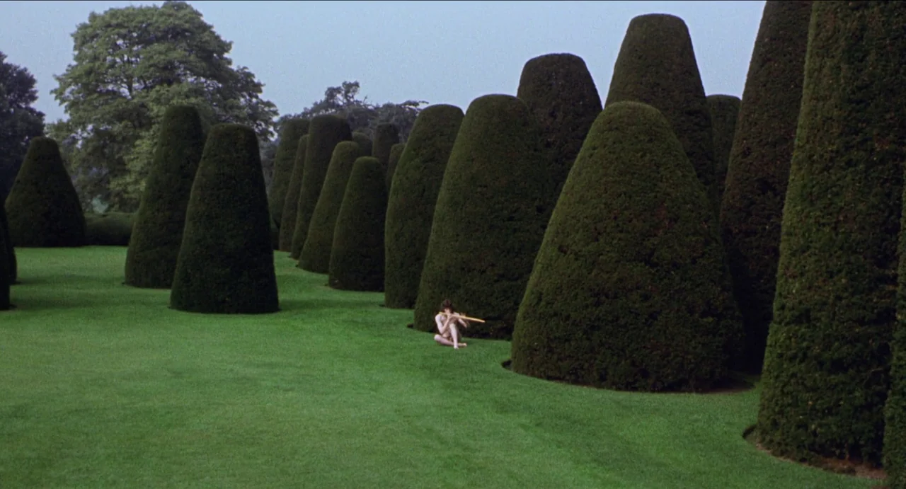 The Canterbury Tales (1972) movie still: wide — A vast expanse of manicured lawn is punctuated by numerous tall, conical topiary shrubs. A single…