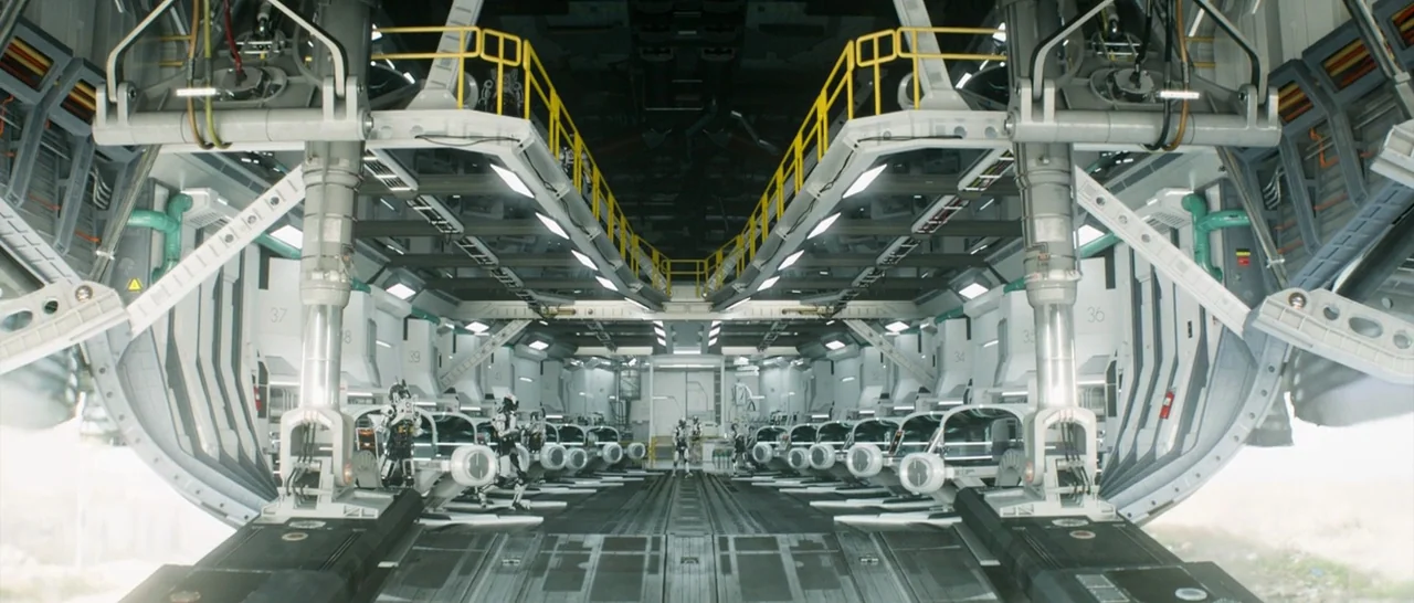 Elysium (2013) movie still: wide — A spacious, symmetrical spacecraft interior features tiered platforms and numbered structural docking bays.…