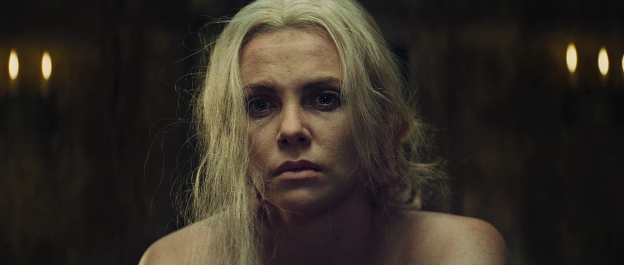 Snow White and The Huntsman (2012) movie still: closeup — A stone chamber features dark walls illuminated by faint flickering candle light. A woman…