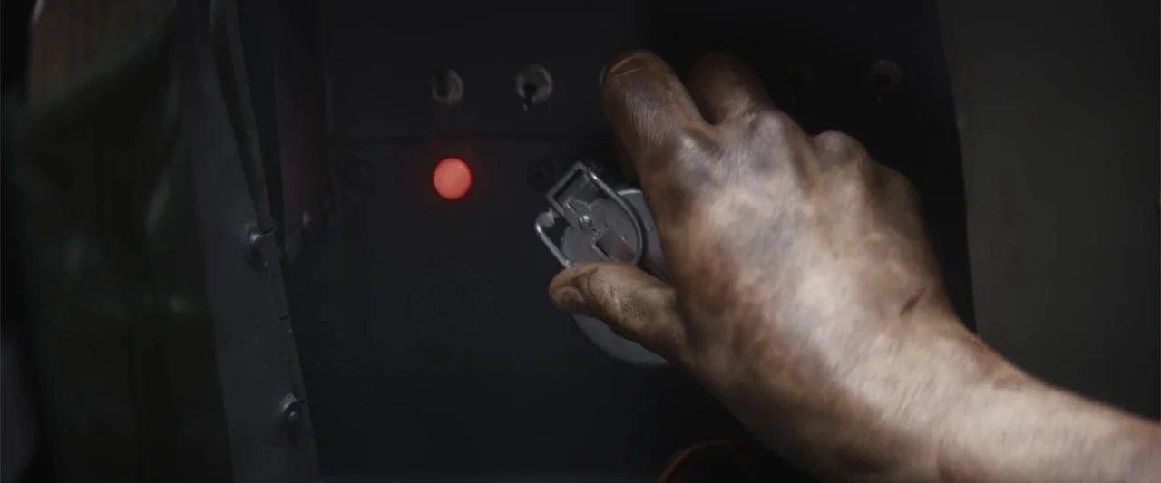 Treblinka's Last Witness (2012) movie still: closeup — The interior of a dark cockpit features a metal switch panel with buttons. A grimy hand…