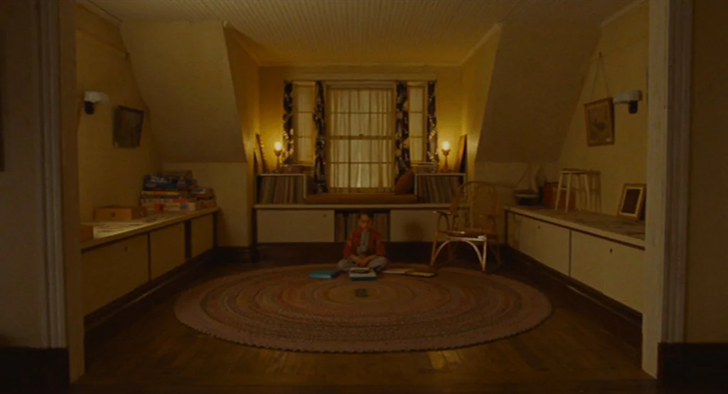 Moonrise Kingdom (2012) movie still: wide — An attic room features a central window with built-in storage cabinets lining the walls. A small boy…