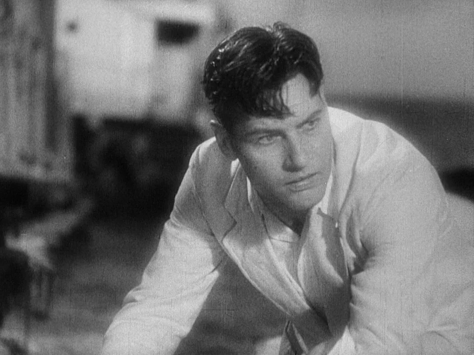 Island of Lost Souls (1932) movie still: closeup — A man stands in an interior room with a blurred background suggesting medical equipment. The man…