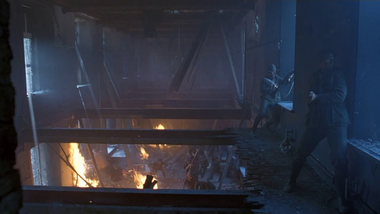 Michael Collins (1996) movie still: wide — A dark, partially destroyed interior features structural steel beams and debris under low light. Soldiers…