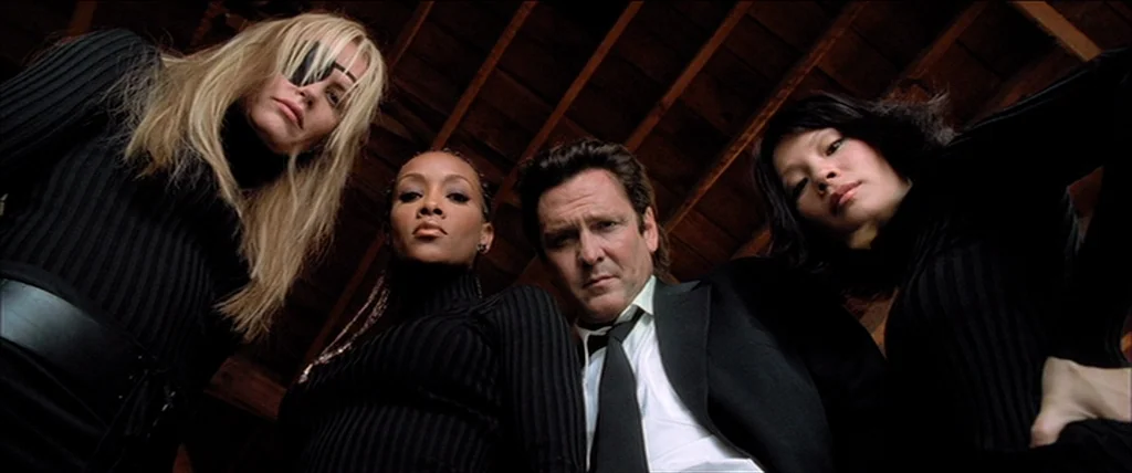 Kill Bill Vol. 1 (2004) movie still: medium — Four people stand together under a exposed wooden ceiling in a rustic interior structure. The group…